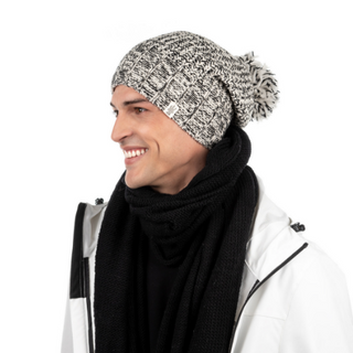 A man wearing a Union Slouch winter hat with a pom-pom and a black scarf smiles while looking to the side, against a white background.