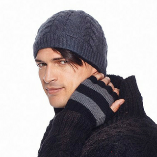 A man wearing a Cable Beanie and sweater posing with his hand on his shoulder.