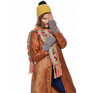A woman in a handmade merino wool brown coat with a Black Pom Beanie and scarf from Nepal.