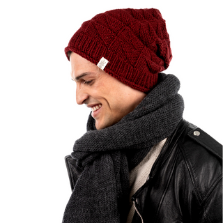 A man wearing a burgundy knitted Wave Slouch beanie and scarf, made from eco-friendly organic cotton.