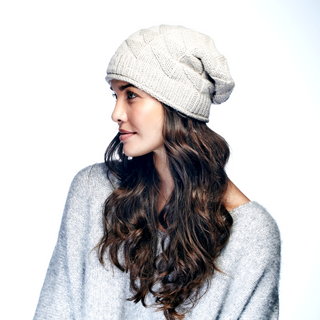 A woman wearing an eco-friendly grey Wave Slouch sweater and a beanie.