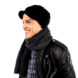A man wearing a black leather jacket, a Knit Jockey Cap, and a gray scarf is smiling and looking to the side against a white background.