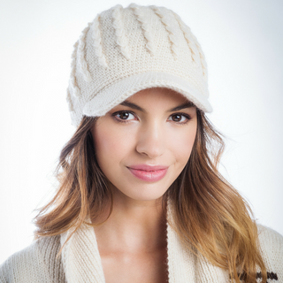 A woman wearing a white Knit Jockey Cap and a matching sweater smiles subtly at the camera.