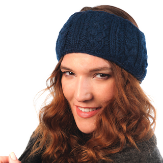 A woman with wavy hair wearing a blue Cable Headband smiles at the camera against a white background.