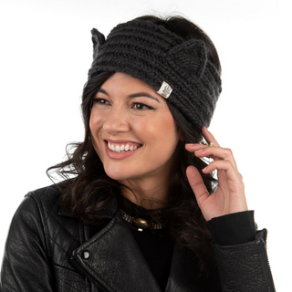 Woman wearing a Kit Kat Headband and leather jacket, smiling while touching her ear.