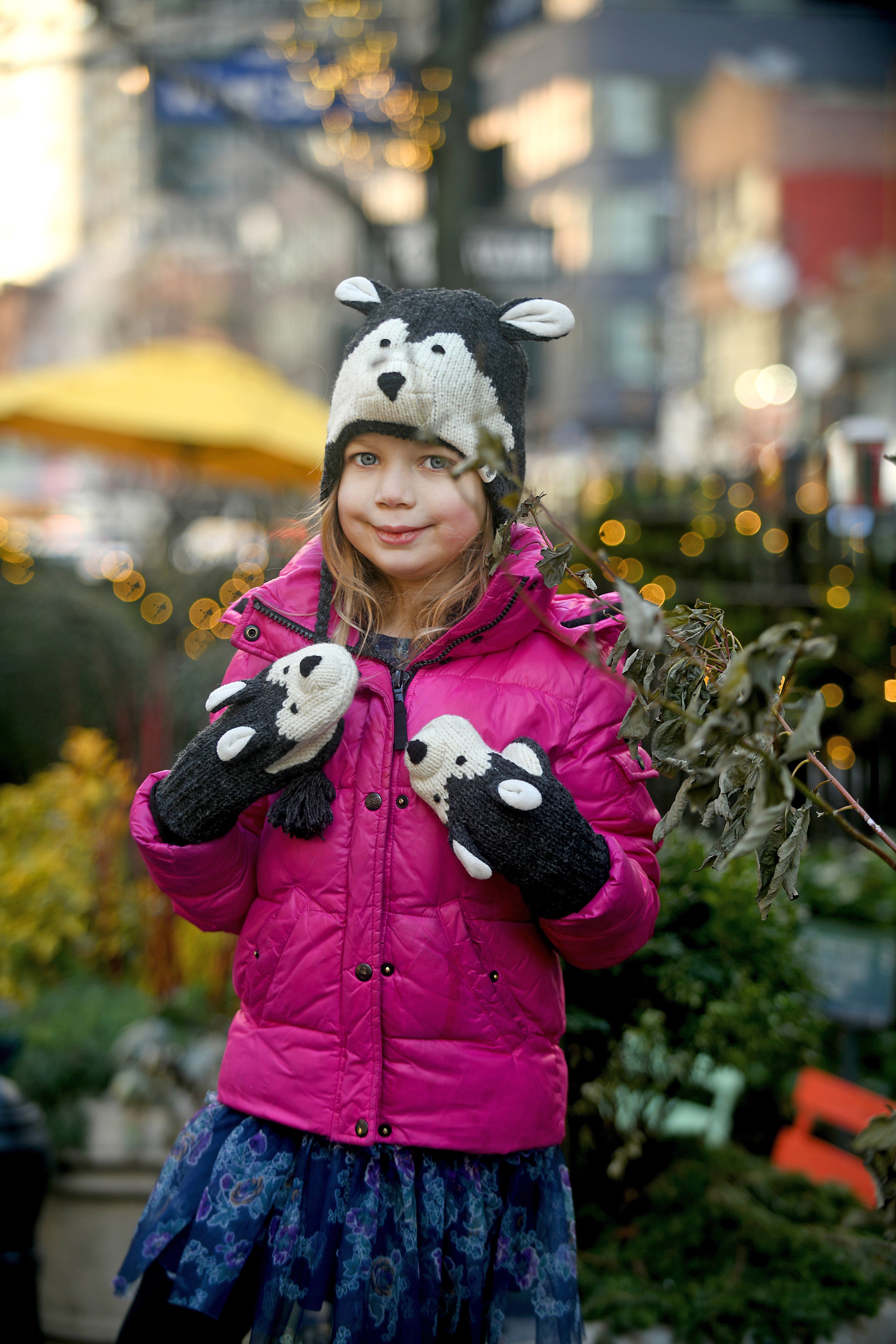 Child in a hand-knit wolf hat and matching mittens