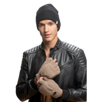A young man faces forward against a plain white background, wearing a black knit beanie, a black leather jacket with quilted shoulders, and Hand Knit Fingerless Gloves With Button Flap and Fleece Lining in brown.