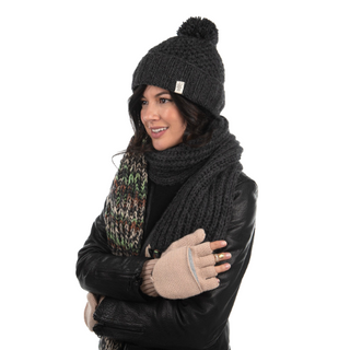 A woman wearing a beanie, scarf, and Bryant Fingerless Gloves with Flap showcases her glowing skin, enhanced by natural ingredients.