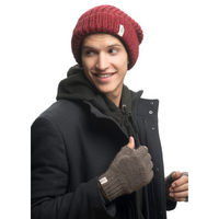 A young man wearing a red knit beanie, dark coat, black hoodie, and Hand Loom Striped and Solid Fingerless Gloves looks to the side with a slight smile. The background is plain white.