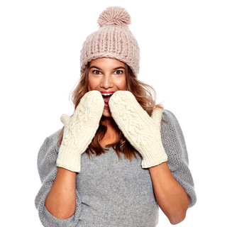 A woman wearing a pink beanie and cream Ball Knit Mittens with Fleece Lining appears to be playfully covering her mouth with her hands.