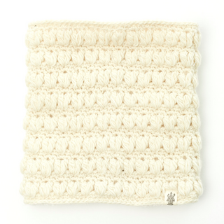 A cream-colored, crocheted Good Vibes Neckwarmer made of merino wool with a visible textured pattern, displayed against a plain background.