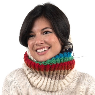 A woman with a joyful expression, wearing a colorful Hi Fidelity Neckwarmer and a cream sweater, isolated on a white background.