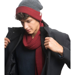 A man wearing a black coat and a handmade Laurent Scarf beanie.