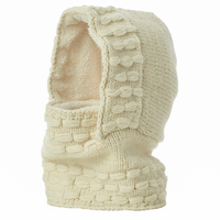 The Hand Knit Legends Hood, a cream-colored knitted balaclava crafted from merino wool and lined with fleece, features a textured pattern. Displayed standing upright on a plain white background, this unisex accessory also functions as a cozy neckwarmer—combining warmth and style for chilly days.