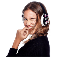 A woman with long brown hair winks and smiles at the camera, wearing Hand Knit Cat Earmuffs with an adjustable band and a black sweater, while holding her hand near her mouth against a plain white background.