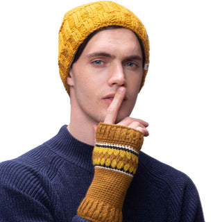 A man wearing Webster handwarmers, a yellow hat and blue sweater with finger on his mouth, made of wool.