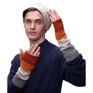Sentence with product name: A young man wearing a white beanie and a blue sweater paired with handmade Colorblock handwarmers from Nepal poses by touching his beanie with one hand and displaying the glove