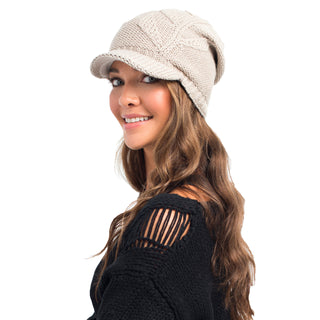 A smiling woman wearing a beige, handmade in Nepal, wool Life Slouch Cap and a black sweater with a torn detail on the sleeve.