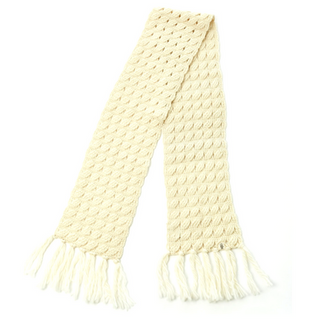 A cream-colored handmade Oslo Scarf with tassels on the ends, isolated on a white background.