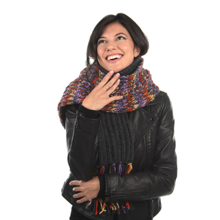 A woman in a black leather jacket and a colorful Prelude Scarf is smiling and looking upwards with her hand on her chest.