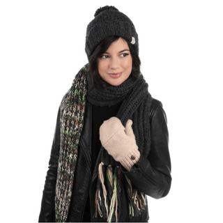A woman wearing winter attire, including a black beanie, gloves, and a black leather jacket, is smiling and looking slightly to the side. Around her neck is a handmade merino wool scarf from Prelude Scarf.